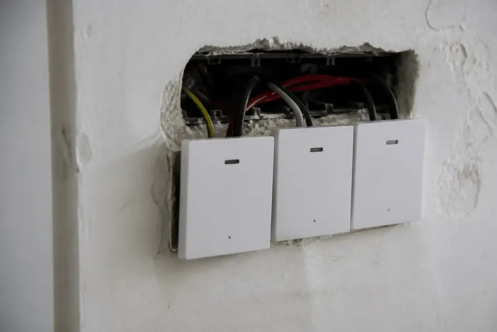 Trois interrupteurs muraux connectes avec fils electriques visibles