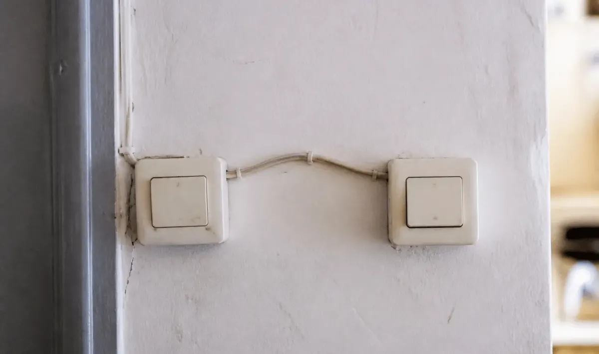 Deux interrupteurs muraux blancs connectes par fils electriques visibles
