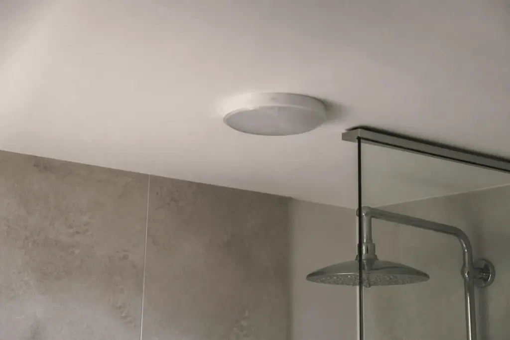 Luminaire etanche installe au plafond pres douche italienne