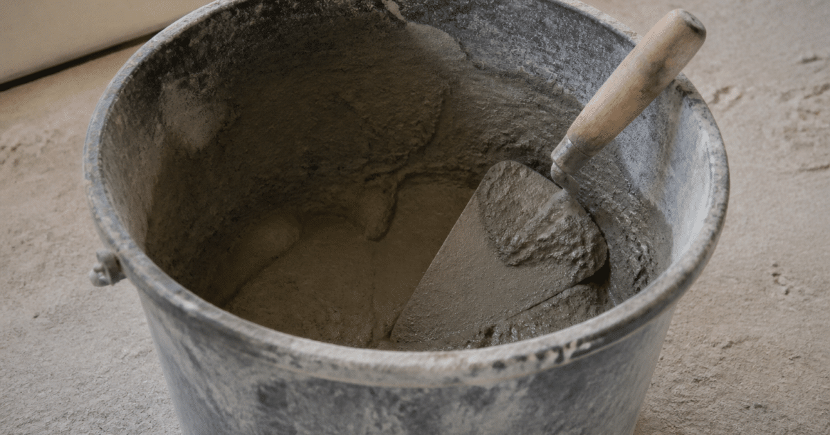 Seau de mortier gris ouvert avec truelle posee dedans