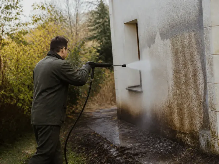 Ouvrier pulverise eau haute pression sur mur exterieur
