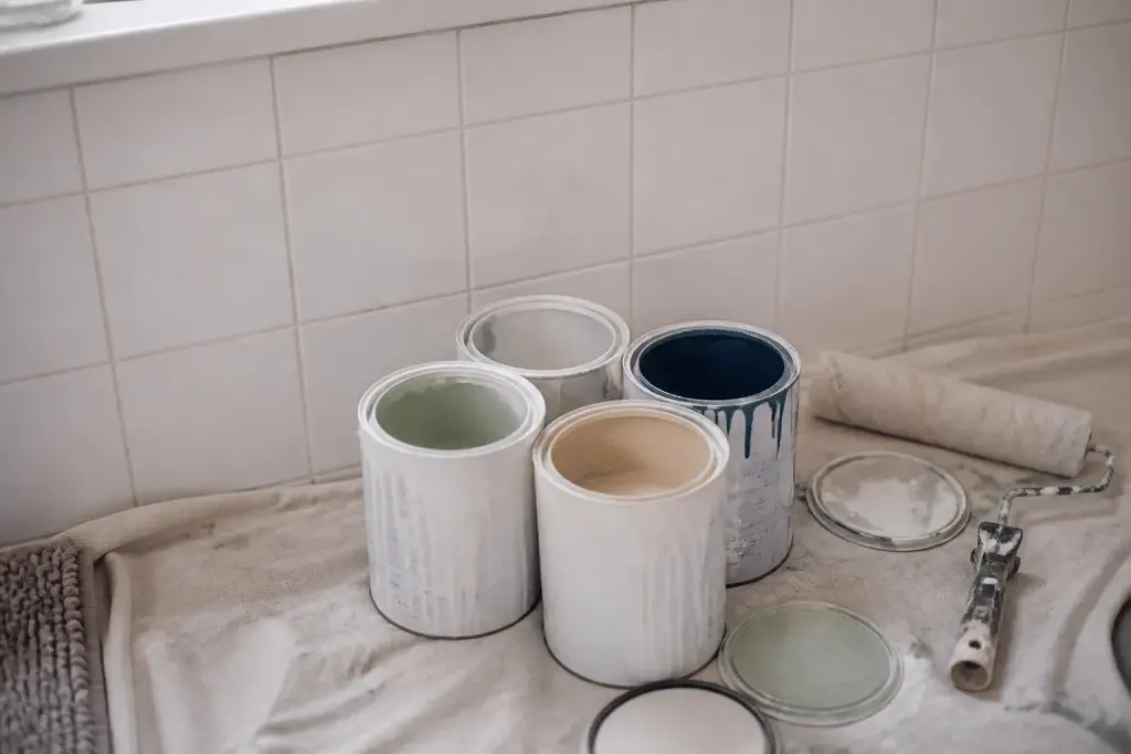 Pots peinture ouverts devant carrelage blanc salle bain
