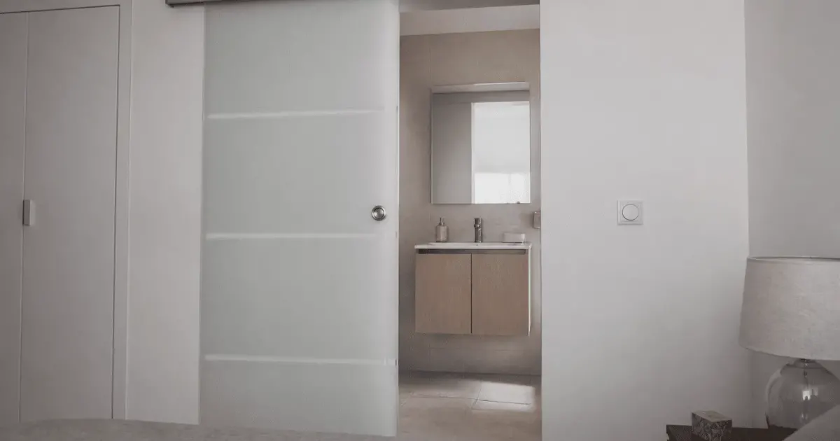 Porte coulissante moderne en verre fermant entree salle bain