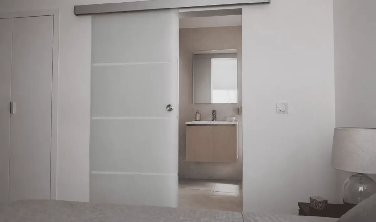 Porte coulissante moderne en verre fermant entree salle bain