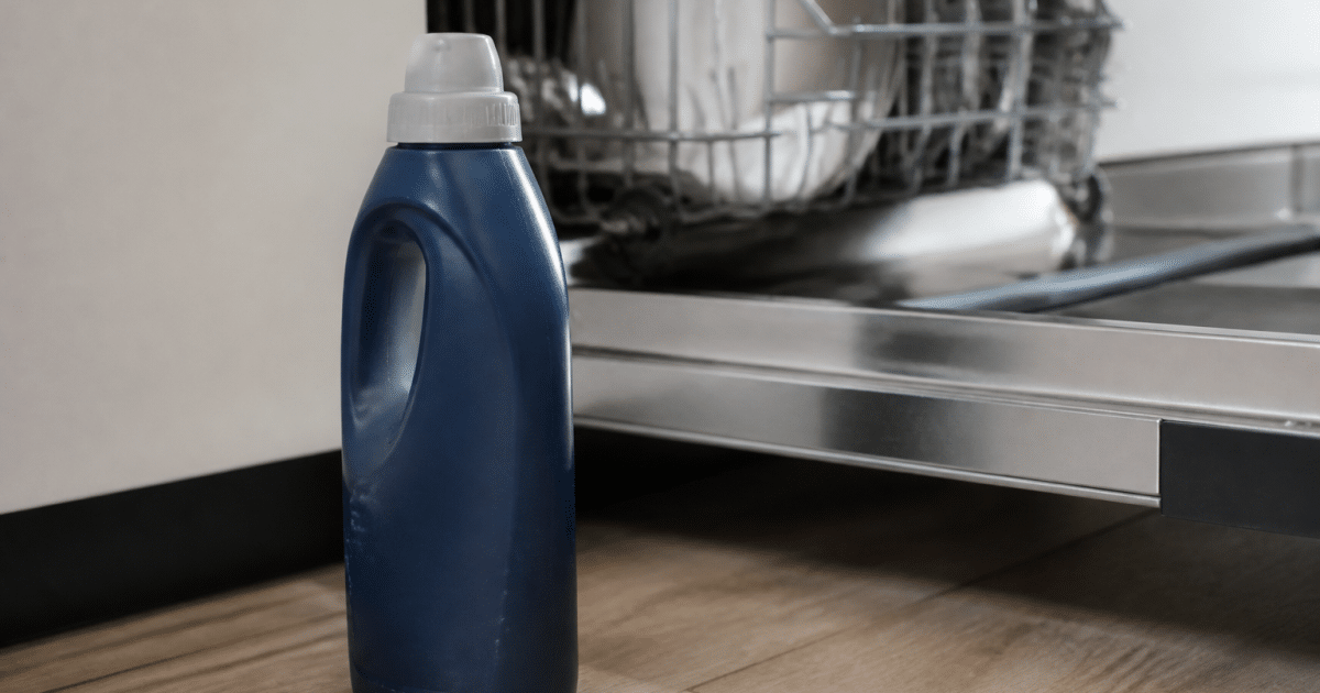 Bouteille de produit de rinçage posée près d'un lave-vaisselle ouvert