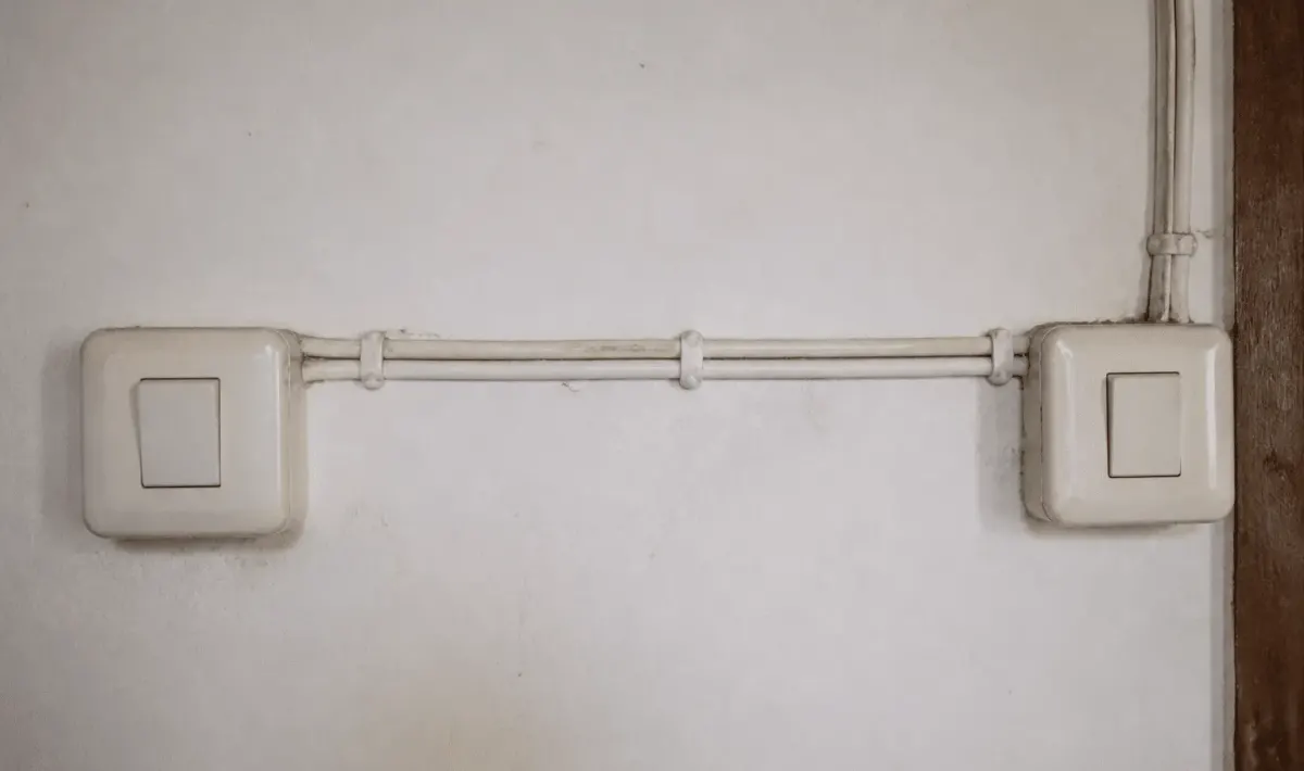 Deux interrupteurs muraux connectes par fils electriques horizontaux