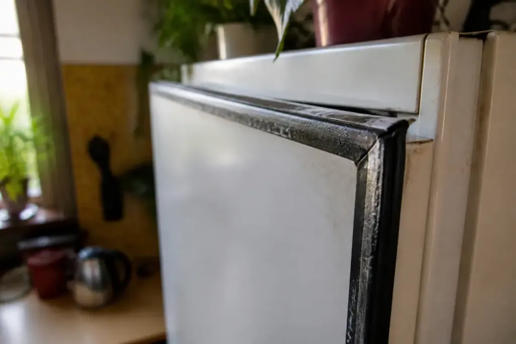 Caoutchouc noir craquele et sale sur un refrigerateur blanc