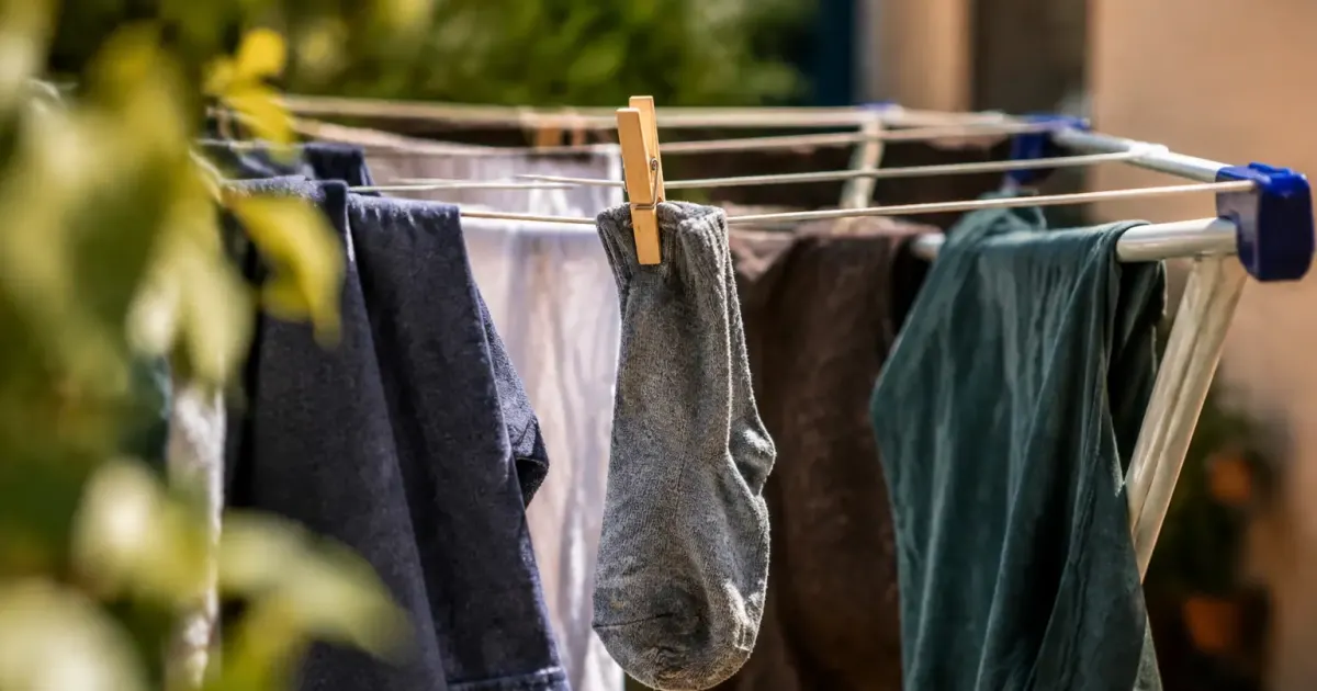 Chaussette suspendue entre des vetements humides sur un etendoir