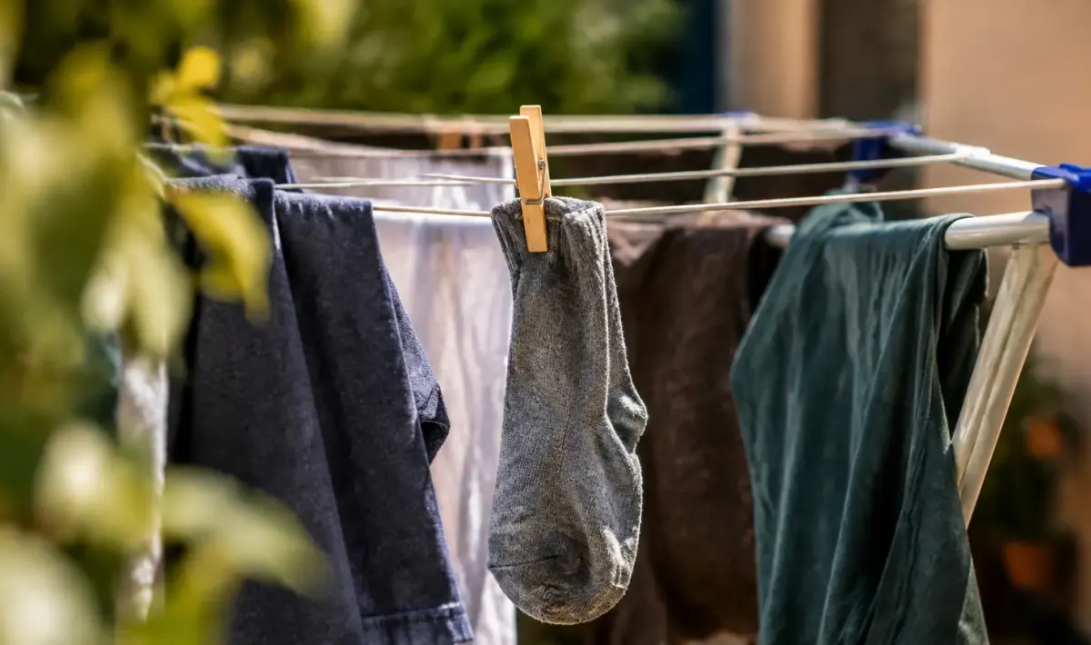Chaussette suspendue entre des vetements humides sur un etendoir