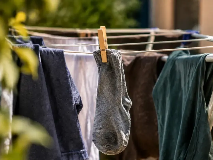 Chaussette suspendue entre des vetements humides sur un etendoir