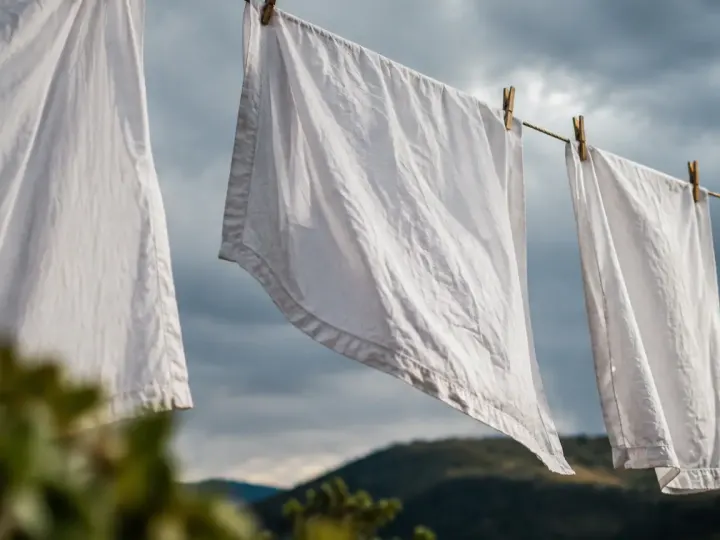 Draps blancs suspendus sur une corde, ciel gris