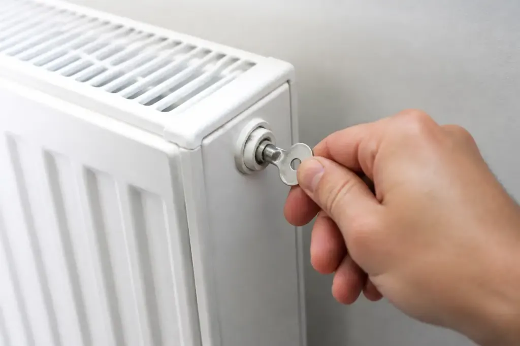 Main tenant une cle de purge sur radiateur blanc