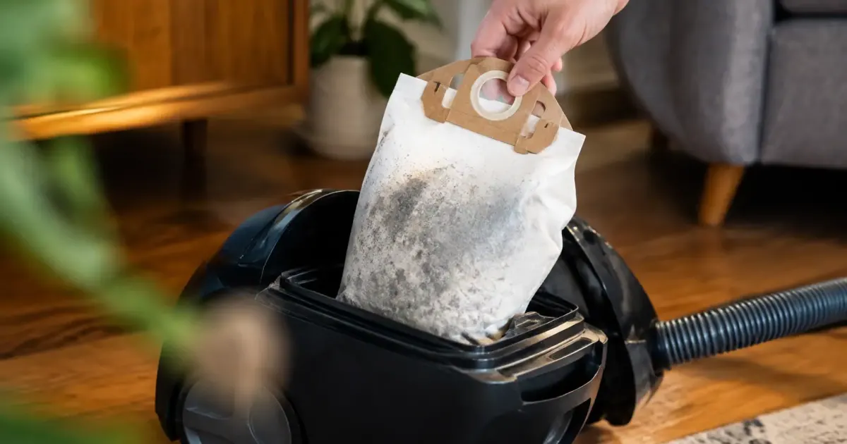 Main gantee retirant un sac poussiere plein