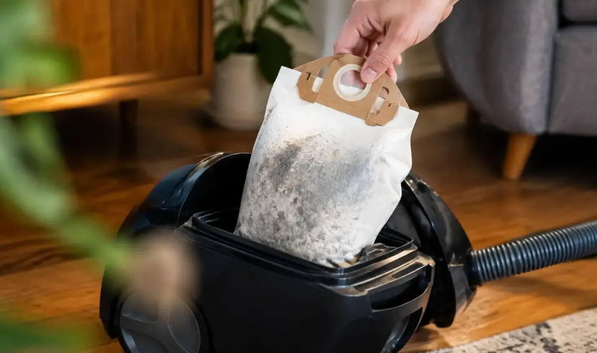 Main gantee retirant un sac poussiere plein