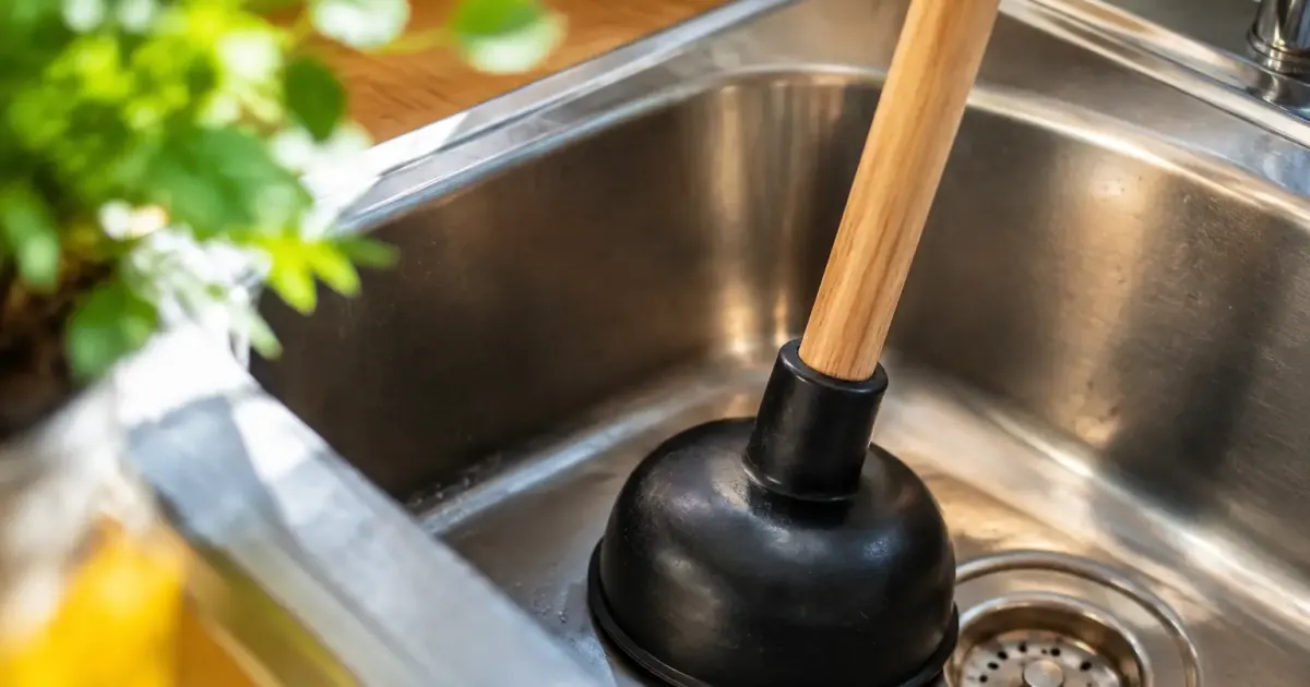 Main tenant une ventouse sur un evier en inox