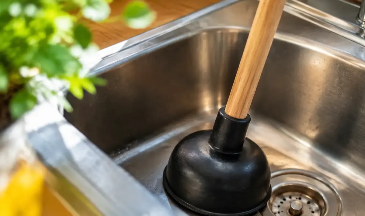 Main tenant une ventouse sur un evier en inox