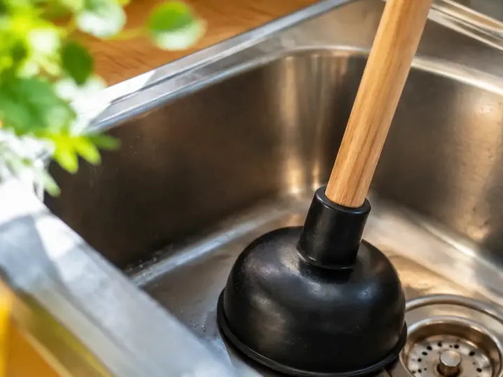 Main tenant une ventouse sur un evier en inox