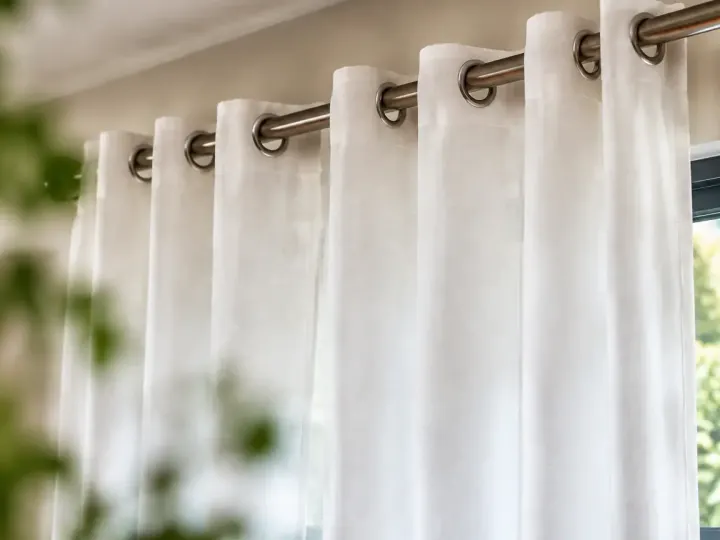 Rideaux blancs tombant droit sur une tringle metallique