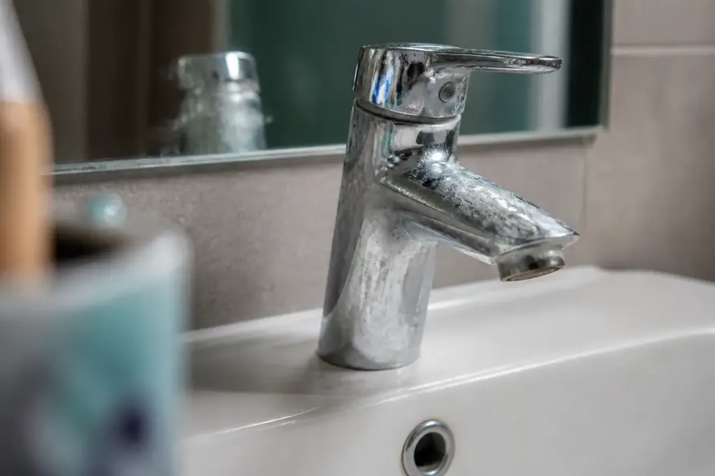 Robinet chrome raye avec traces blanches de calcaire
