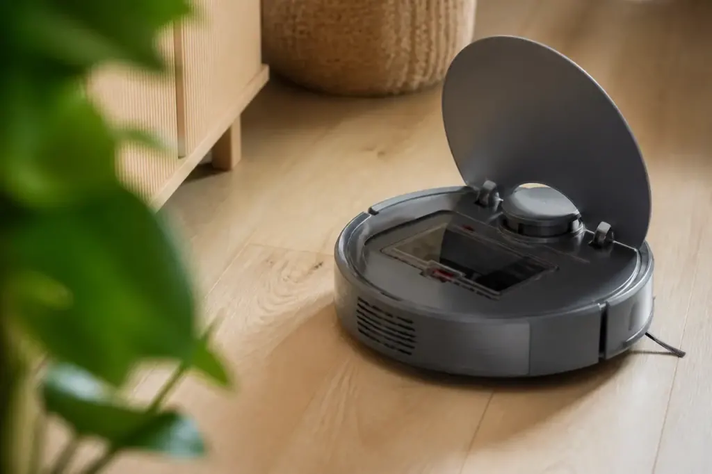 Robot aspirateur gris sur parquet clair avec couvercle ouvert