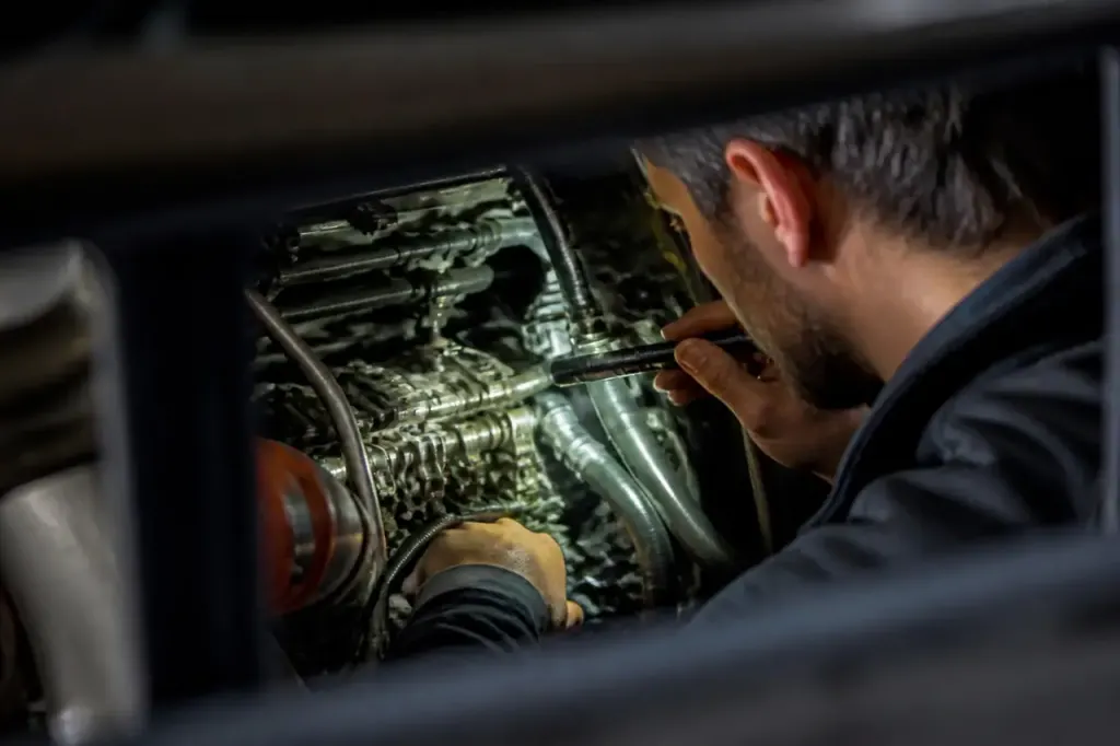 Technicien inspecte moteur ouvert avec lampe torche